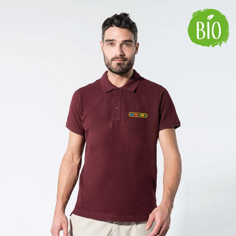 Homme debout avec un polo en coton bio 100 %. Le polo est imprimé en couleurs au niveau du coeur